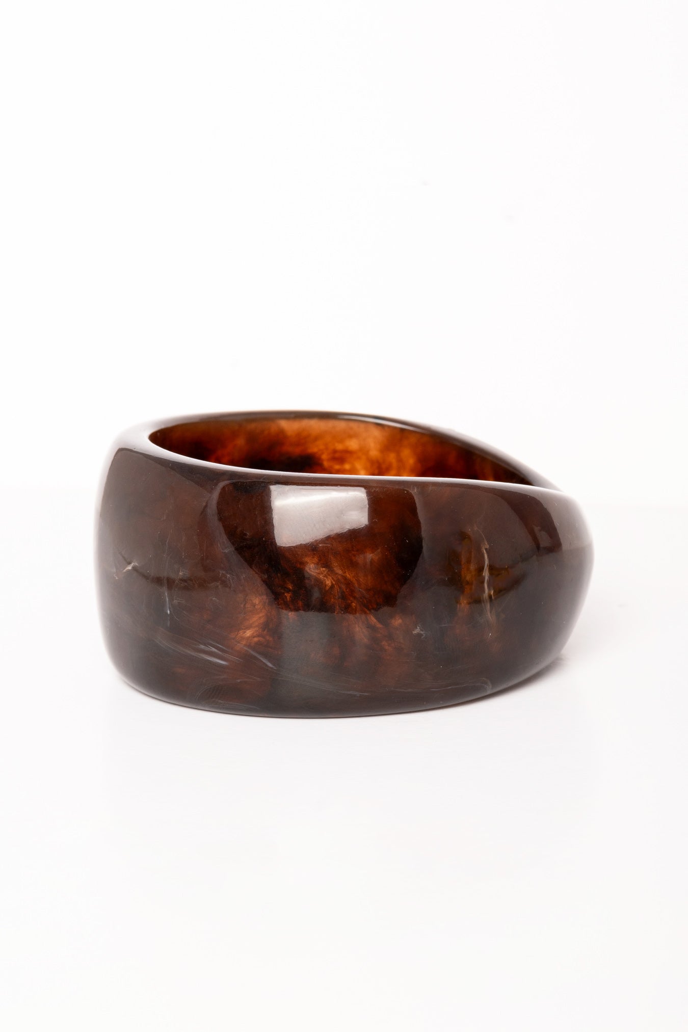 “Plano detalle del Brazalete Lola de resina marrón oscuro, destacando su superficie pulida y textura marmoleada.”