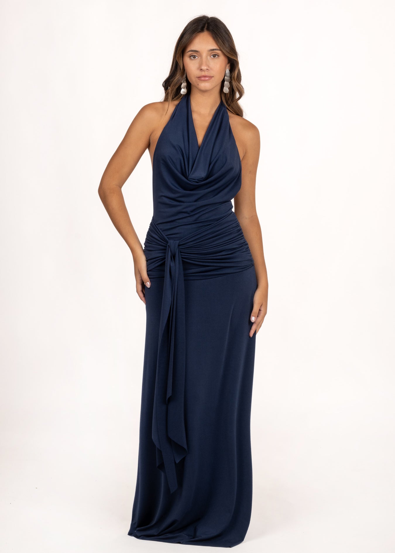 Vestido Kala azul noche, ideal como vestido de invitada de otoño o vestido de graduación. Su escote en cascada y fruncido realzan la figura, mientras la lazada lateral y la espalda descubierta aportan un toque elegante y sofisticado para ocasiones especiales.