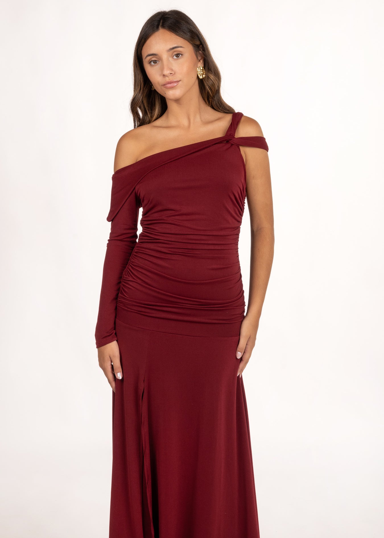 El Vestido Ovara Granate es perfecto para eventos especiales. Destaca por su escote asimétrico con manga larga y doble tirante cruzado. Los frunces laterales realzan la figura, ofreciendo un diseño sofisticado y favorecedor. Es ideal como vestido de graduación o vestido de invitada de otoño para cualquier ocasión que requiera un toque de estilo y distinción.
