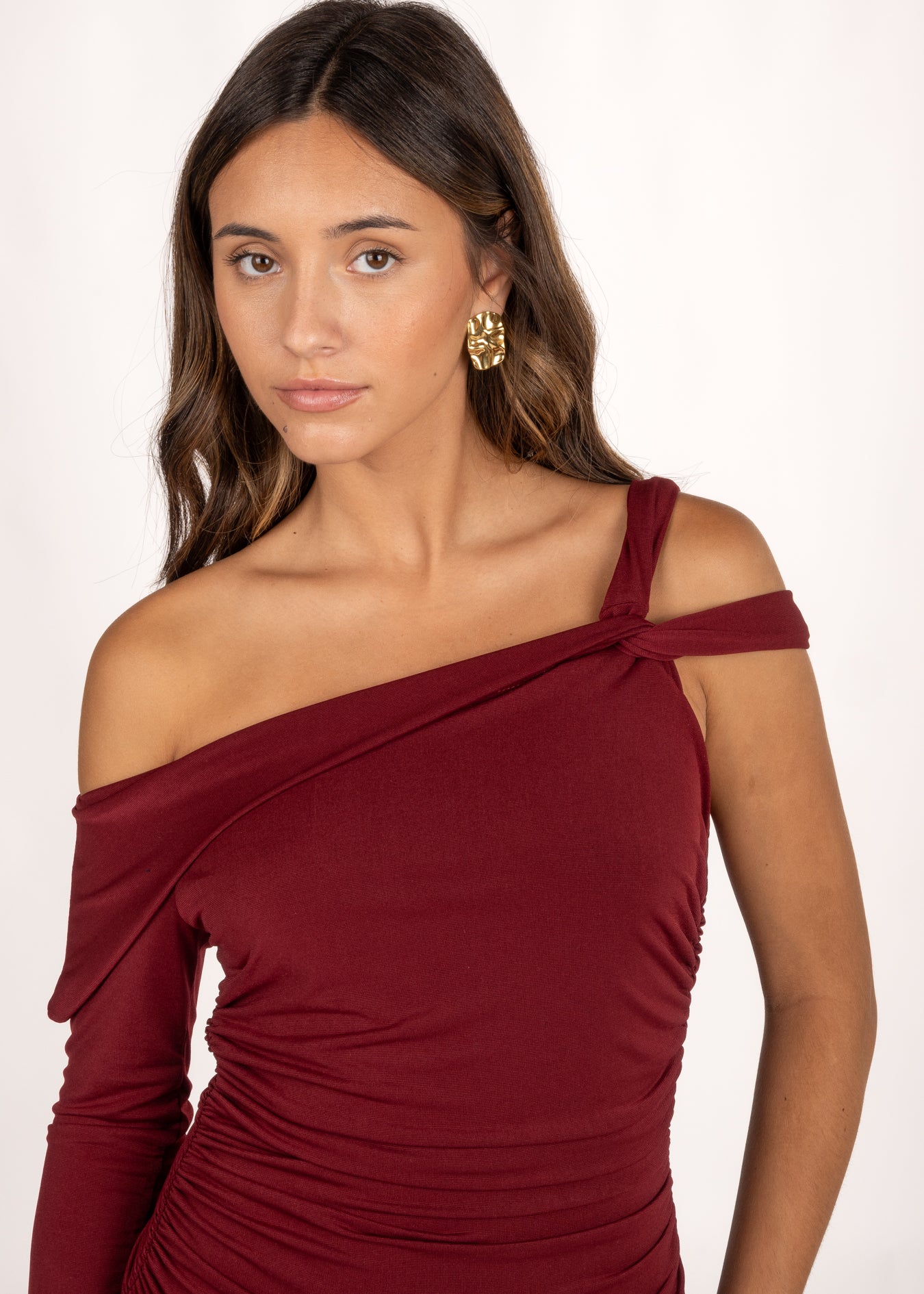 El Vestido Ovara Granate es perfecto para eventos especiales. Destaca por su escote asimétrico con manga larga y doble tirante cruzado. Los frunces laterales realzan la figura, ofreciendo un diseño sofisticado y favorecedor. Es ideal como vestido de graduación o vestido de invitada de otoño para cualquier ocasión que requiera un toque de estilo y distinción.