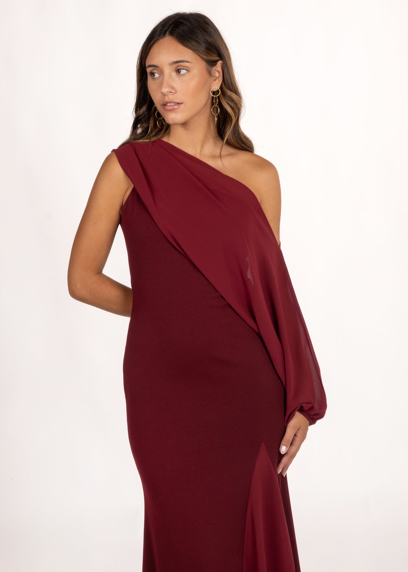 Vestido asimétrico color granate con manga extraíble, perfecto para un look de invitada de otoño. Su diseño versátil ofrece dos estilos: uno sofisticado con manga fluida, y otro más minimalista y elegante sin ella. La falda con godete aporta movimiento, ideal para bodas, galas y eventos especiales.