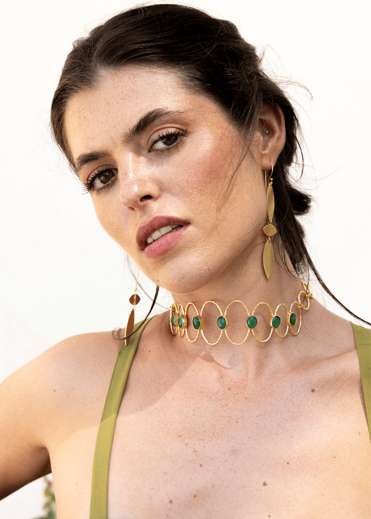 Choker Deriva Verde, collar dorado con piedras verdes, sobre vestido verde oliva