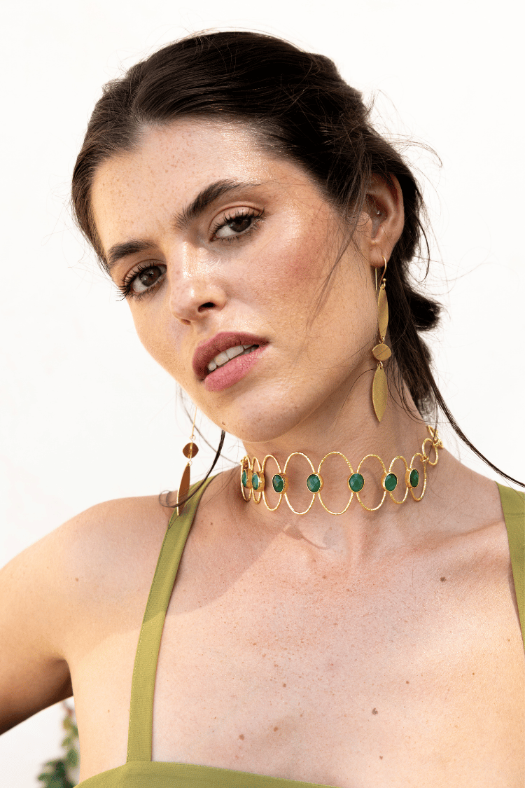 Choker Deriva Verde, collar dorado con piedras verdes, sobre vestido verde oliva