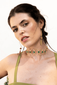Choker Deriva Verde, collar dorado con piedras verdes, sobre vestido verde oliva