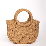 Bolso de rafia trenzada color camel con asas redondas rígidas y forma semiluna.
