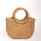 Bolso de rafia trenzada color camel con asas redondas rígidas y forma semiluna.