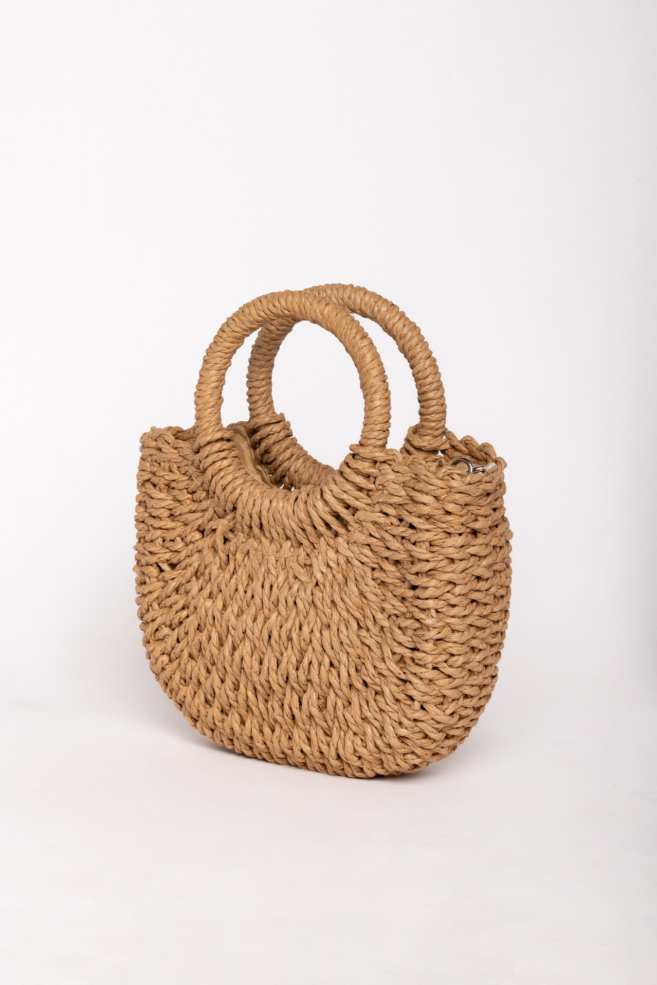 Vista lateral del bolso de rafia camel con asas circulares.