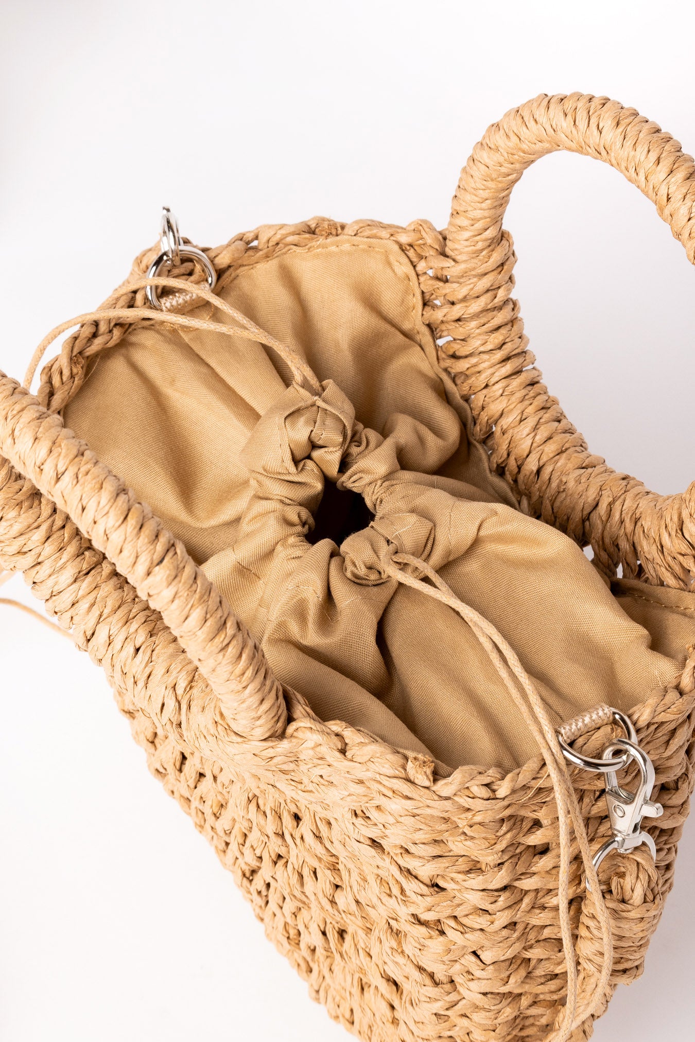 Interior del bolso de rafia camel con cierre de saco ajustable en tela.