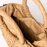 Detalle del interior del bolso de rafia camel mostrando bolsillo interior y forro de tela.