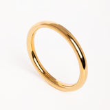 Brazalete dorado de diseño minimalista fotografiado en vista superior sobre fondo blanco