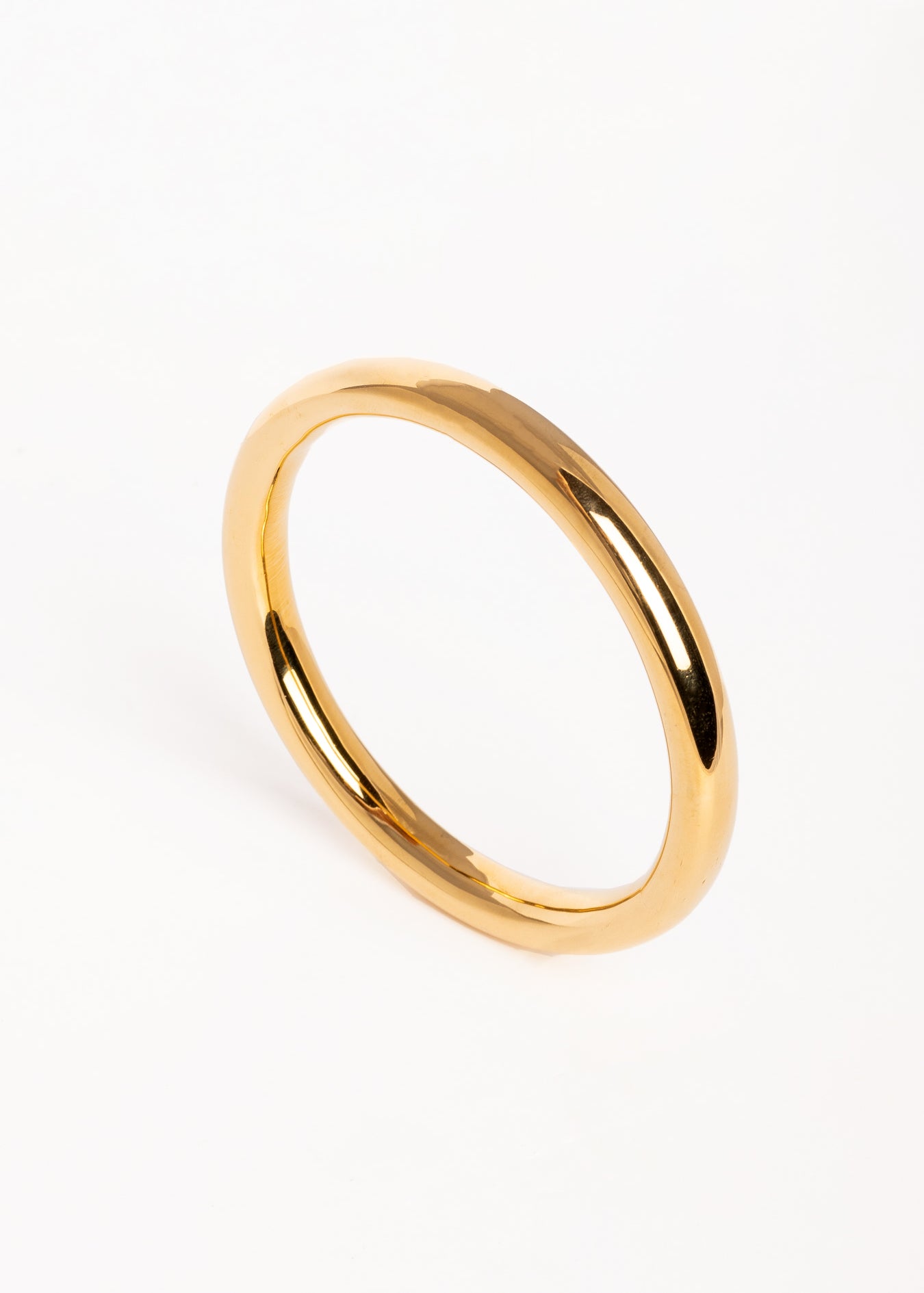 Brazalete dorado de diseño minimalista fotografiado en vista superior sobre fondo blanco