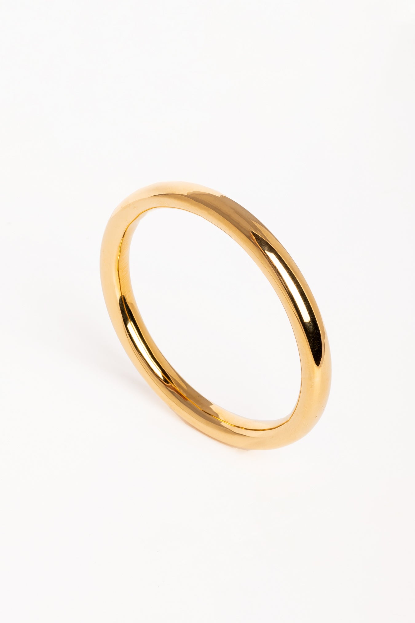Brazalete dorado de diseño minimalista fotografiado en vista superior sobre fondo blanco