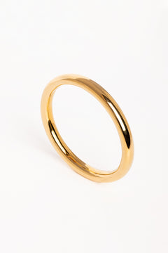 Brazalete dorado de diseño minimalista fotografiado en vista superior sobre fondo blanco