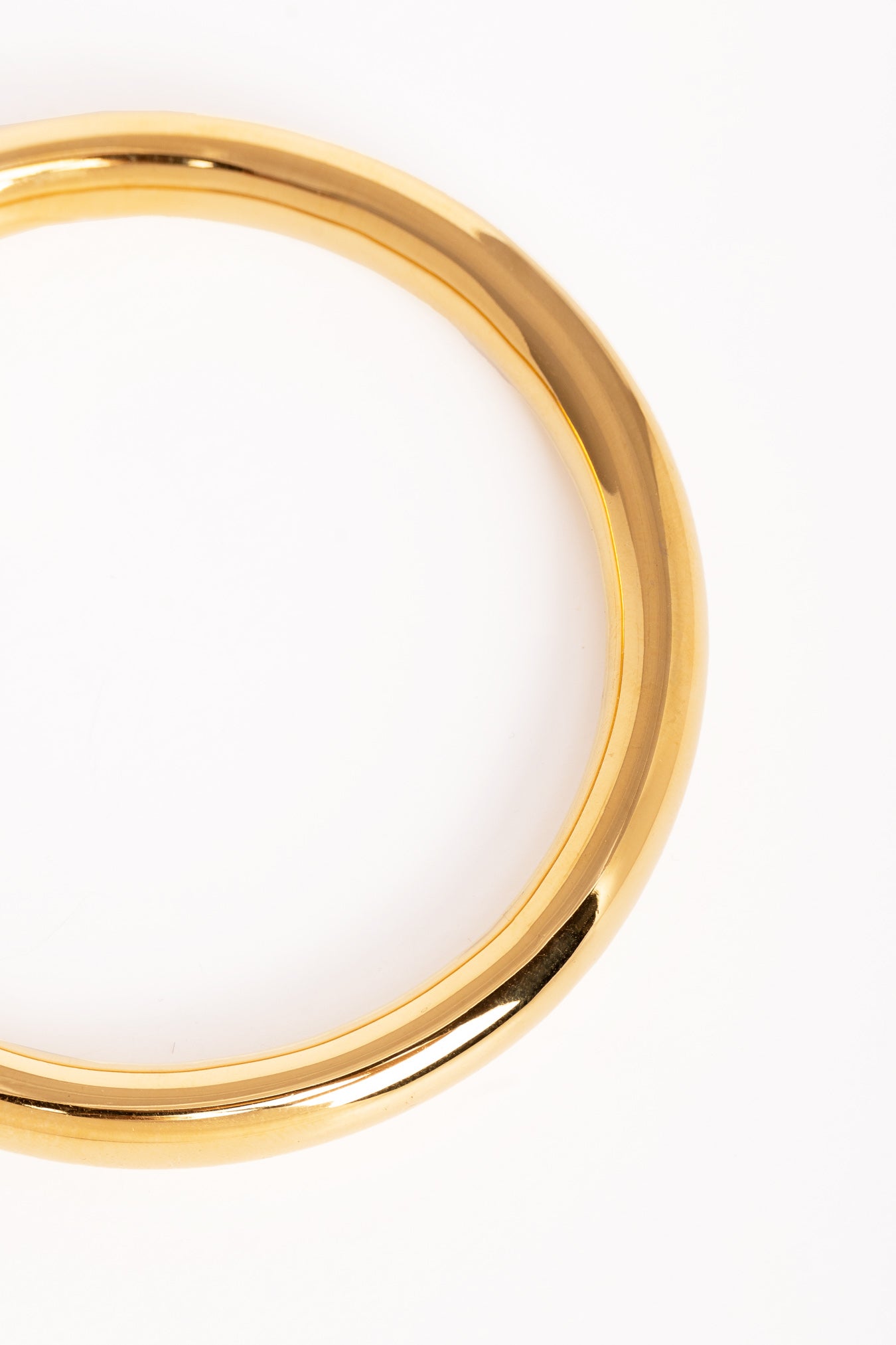 Plano detalle del brazalete dorado, destacando su superficie pulida y curvatura elegante.”