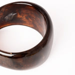  “Brazalete Lola fotografiado en vista frontal, mostrando su diseño ancho y efecto brillante.”