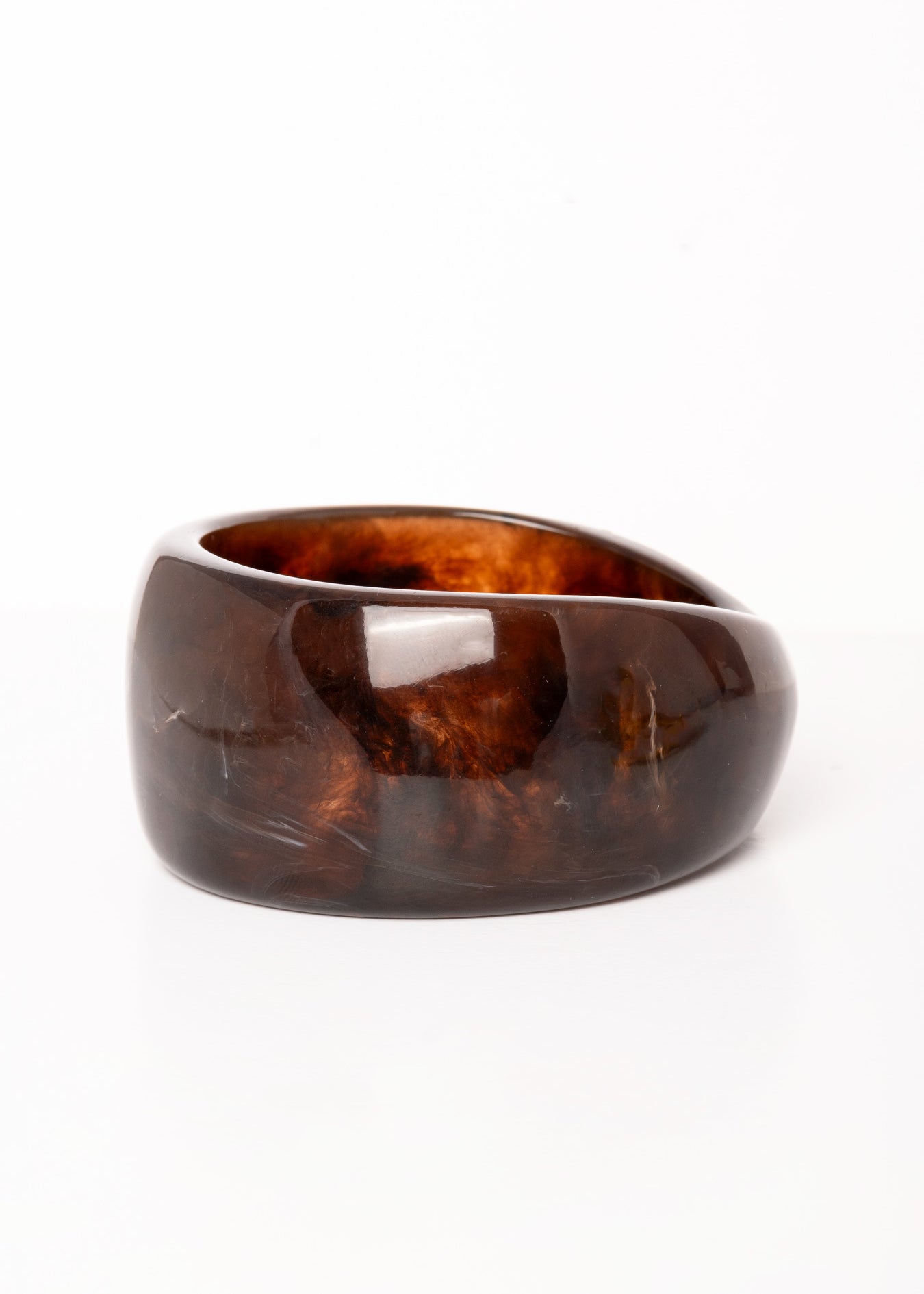  “Plano detalle del Brazalete Lola de resina marrón oscuro, destacando su superficie pulida y textura marmoleada.”