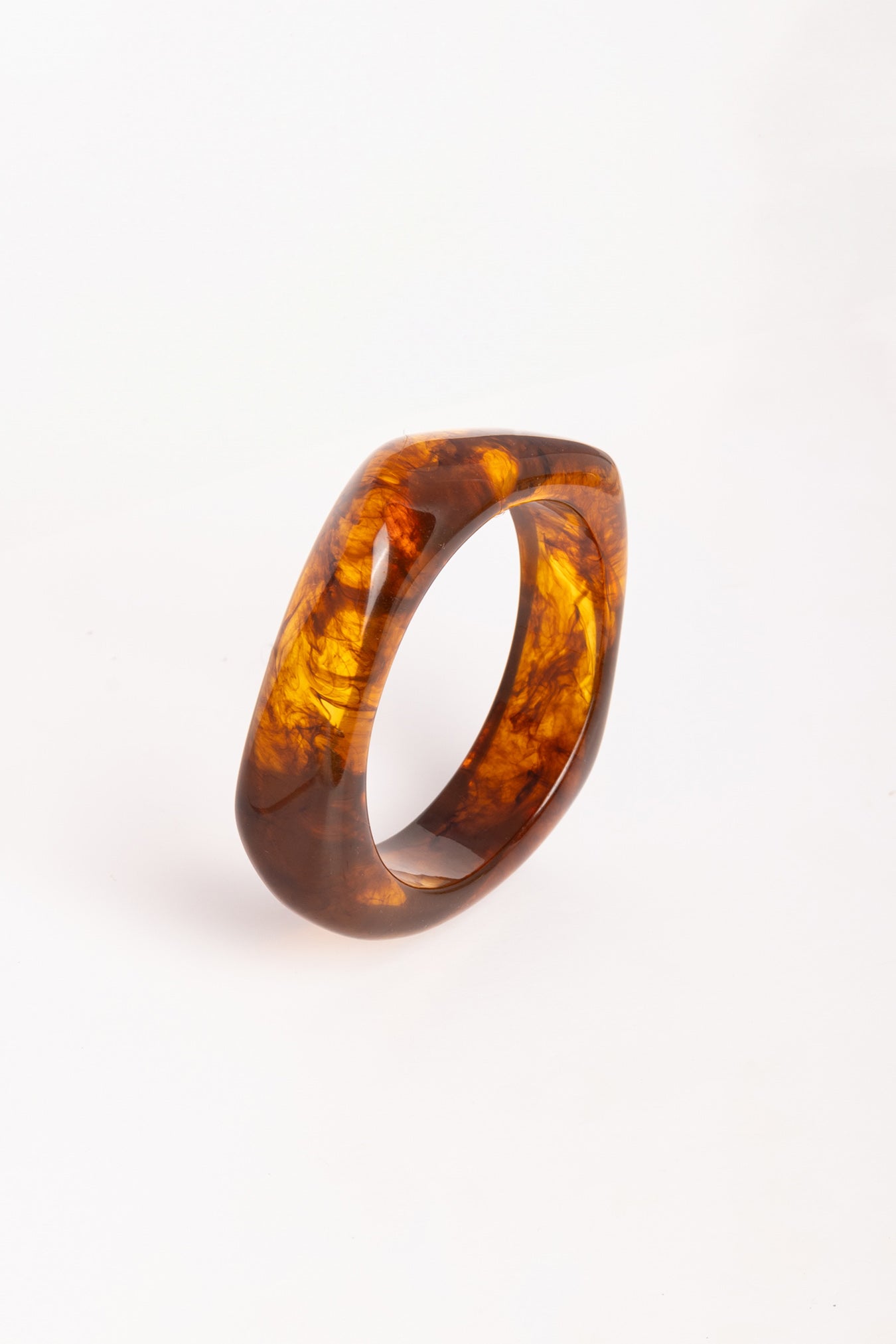 “Brazalete Regina Ámbar de resina con efecto marmoleado, en vista superior sobre fondo blanco.”