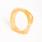“Brazalete Regina Beige de resina con efecto marmoleado, vista superior sobre fondo blanco.”