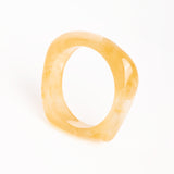 “Brazalete Regina Beige de resina con efecto marmoleado, vista superior sobre fondo blanco.”