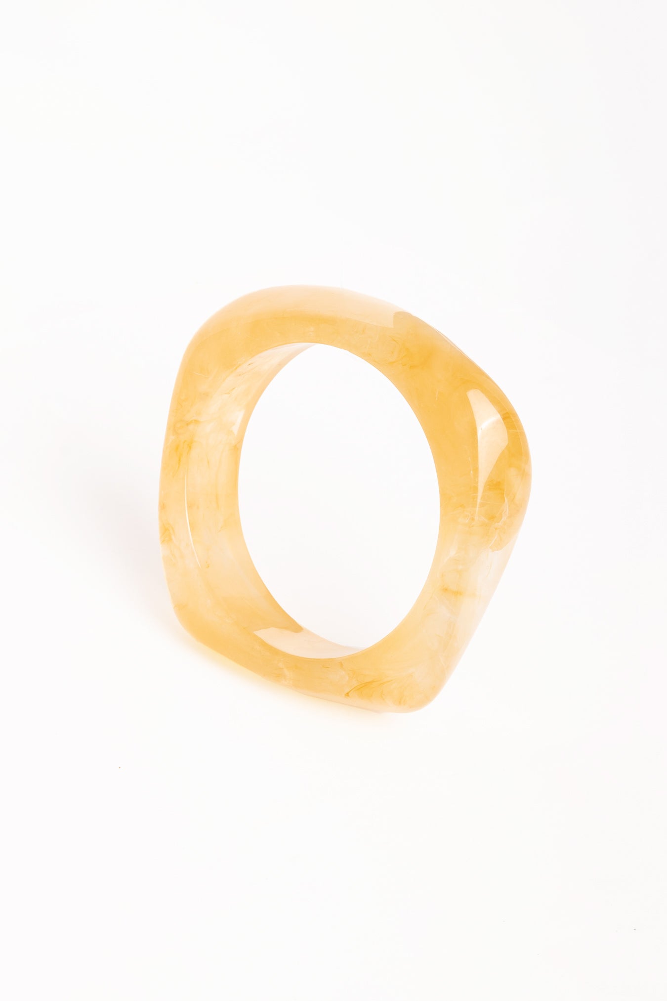 “Brazalete Regina Beige de resina con efecto marmoleado, vista superior sobre fondo blanco.”