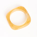 “Brazalete Regina Beige en posición vertical, mostrando su forma cuadrada y textura translúcida sobre fondo blanco.”