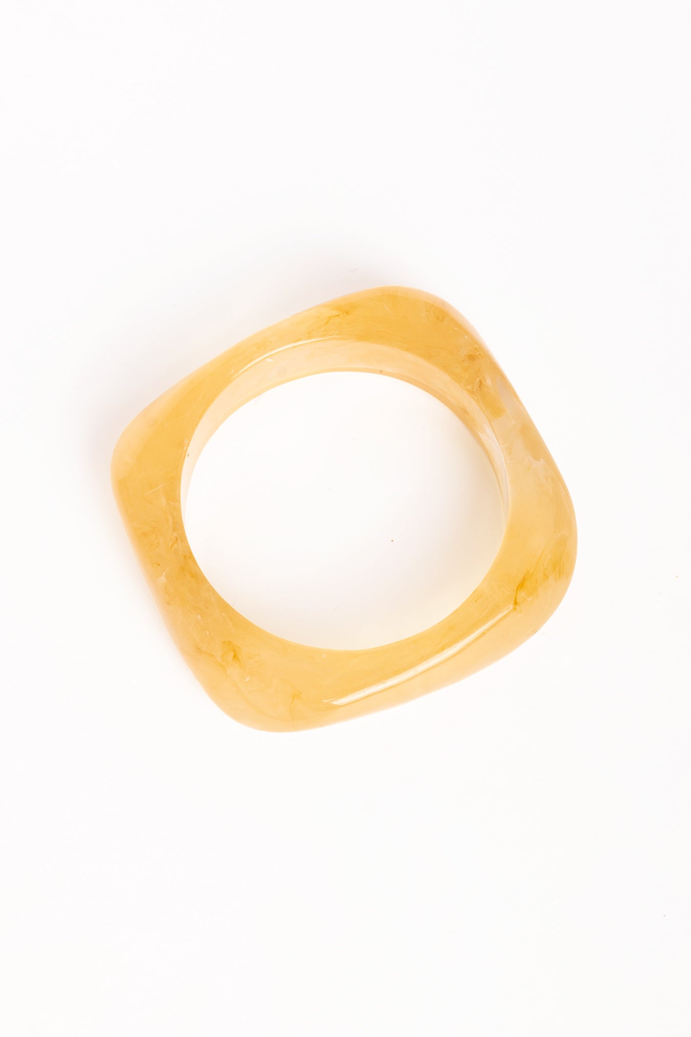 “Brazalete Regina Beige en posición vertical, mostrando su forma cuadrada y textura translúcida sobre fondo blanco.”
