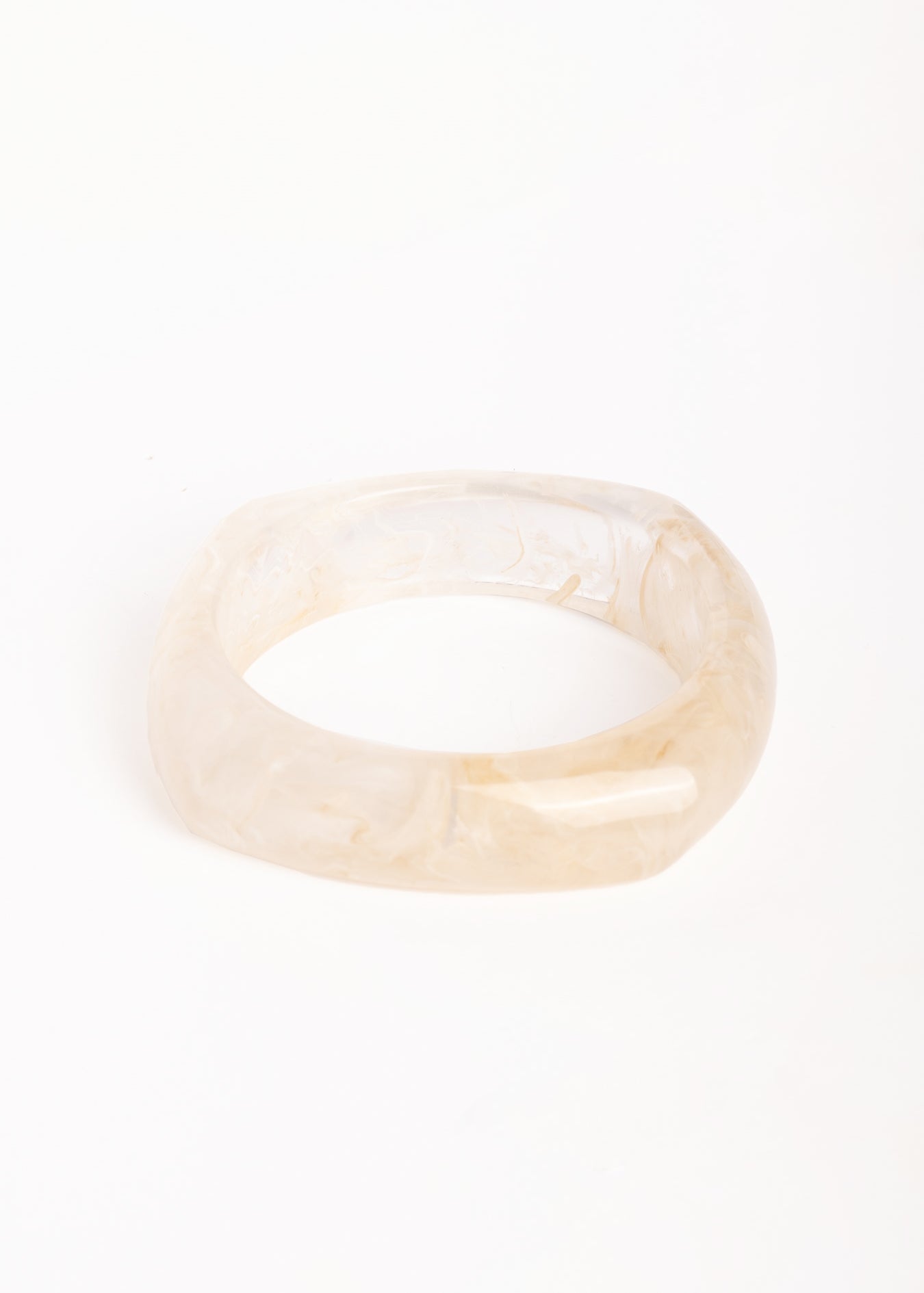 “Brazalete de resina efecto mármol en tono marfil, con forma cuadrada y bordes redondeados, fotografiado sobre fondo blanco.”