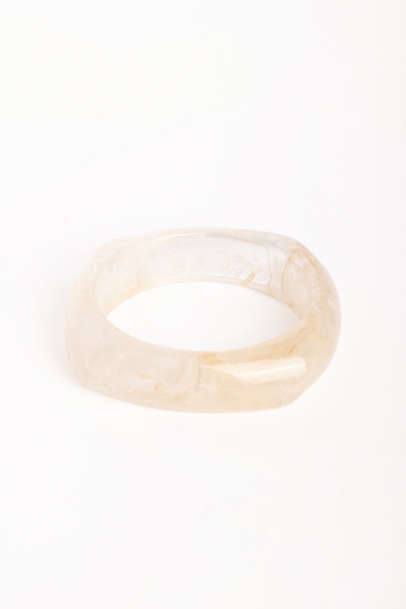 “Brazalete de resina efecto mármol en tono marfil, con forma cuadrada y bordes redondeados, fotografiado sobre fondo blanco.”