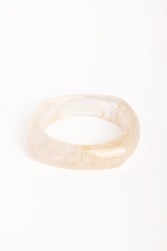 “Brazalete de resina efecto mármol en tono marfil, con forma cuadrada y bordes redondeados, fotografiado sobre fondo blanco.”