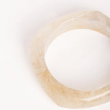  “Plano detalle del brazalete de resina marfil, mostrando su acabado traslúcido y forma geométrica.”