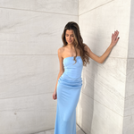 Modelo con vestido largo celeste palabra de honor, de silueta entallada con drapeado en la cadera.