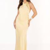 Modelo con vestido largo amarillo de escote halter y tejido fluido.