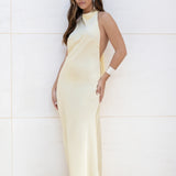 Vista frontal de modelo con vestido largo amarillo de satén escote halter.