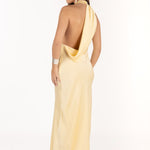 Modelo con vestido largo amarillo,  espalda descubierta y de tejido fluido.