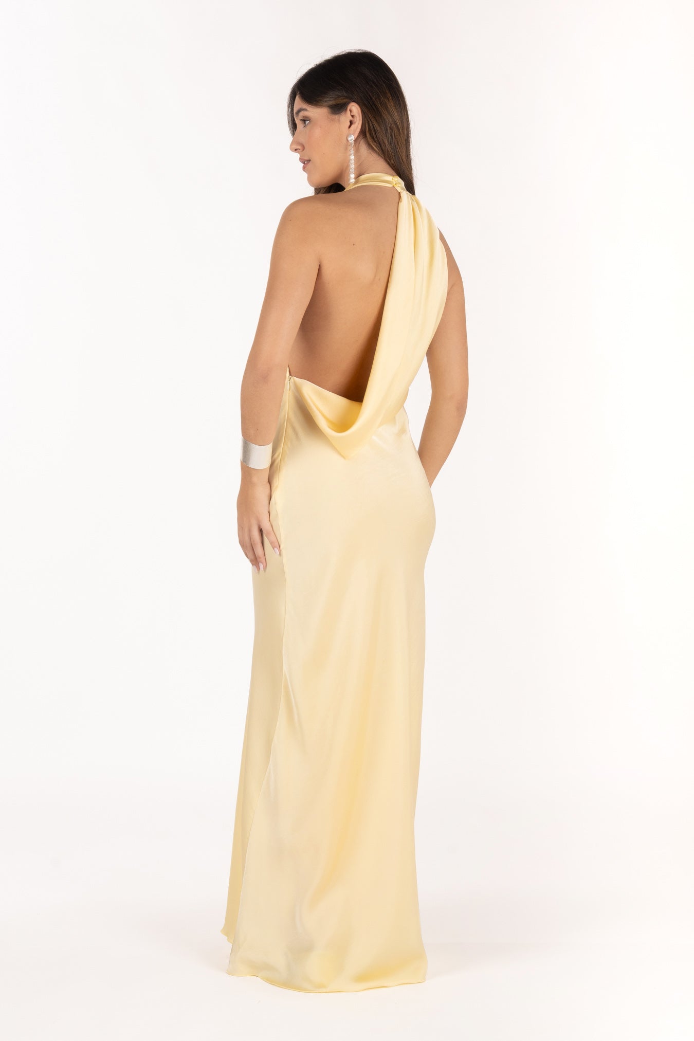 Modelo con vestido largo amarillo,  espalda descubierta y de tejido fluido.