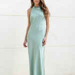 Vista frontal de modelo con vestido largo color menta de satén y escote halter.