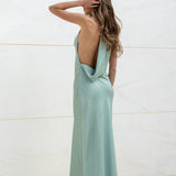 Vista posterior de modelo con vestido largo color menta de satén y espalda descubierta.