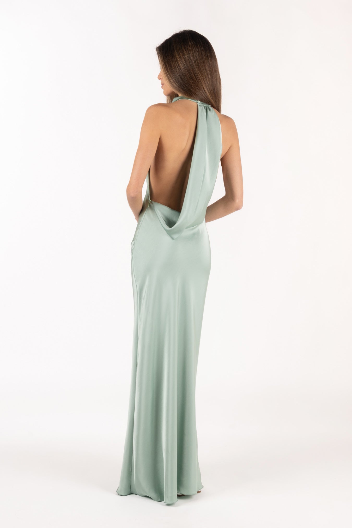 Vista posterior de modelo con vestido largo color menta de satén y espalda descubierta.