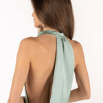 Detalle vista posterior de modelo con vestido color menta y espalda descubierta.