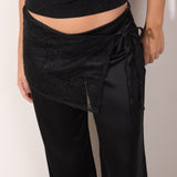 pañuelo tipo pareo de encaje negro, un accesorio versátil que eleva cualquier look. Diseñado para usarse atado a la cintura, este pañuelo combina delicadeza y sofisticación gracias a su textura semitransparente y detalles en encaje floral.