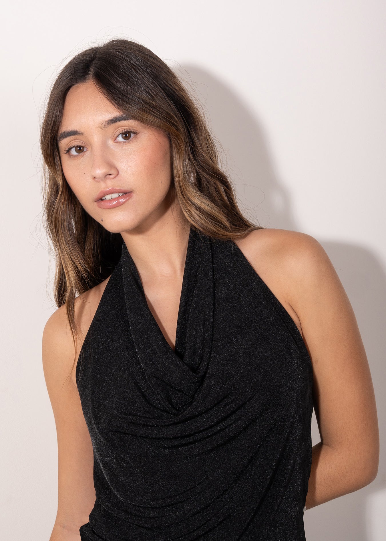 Modelo con Top negro con escote drapeado tipo halter, estilo elegante y femenino