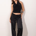 Modelo posando con top negro con escote drapeado tipo halter, estilo elegante y femenino