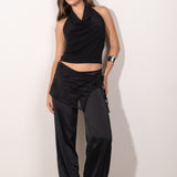 Modelo posando con top negro con escote drapeado tipo halter, estilo elegante y femenino