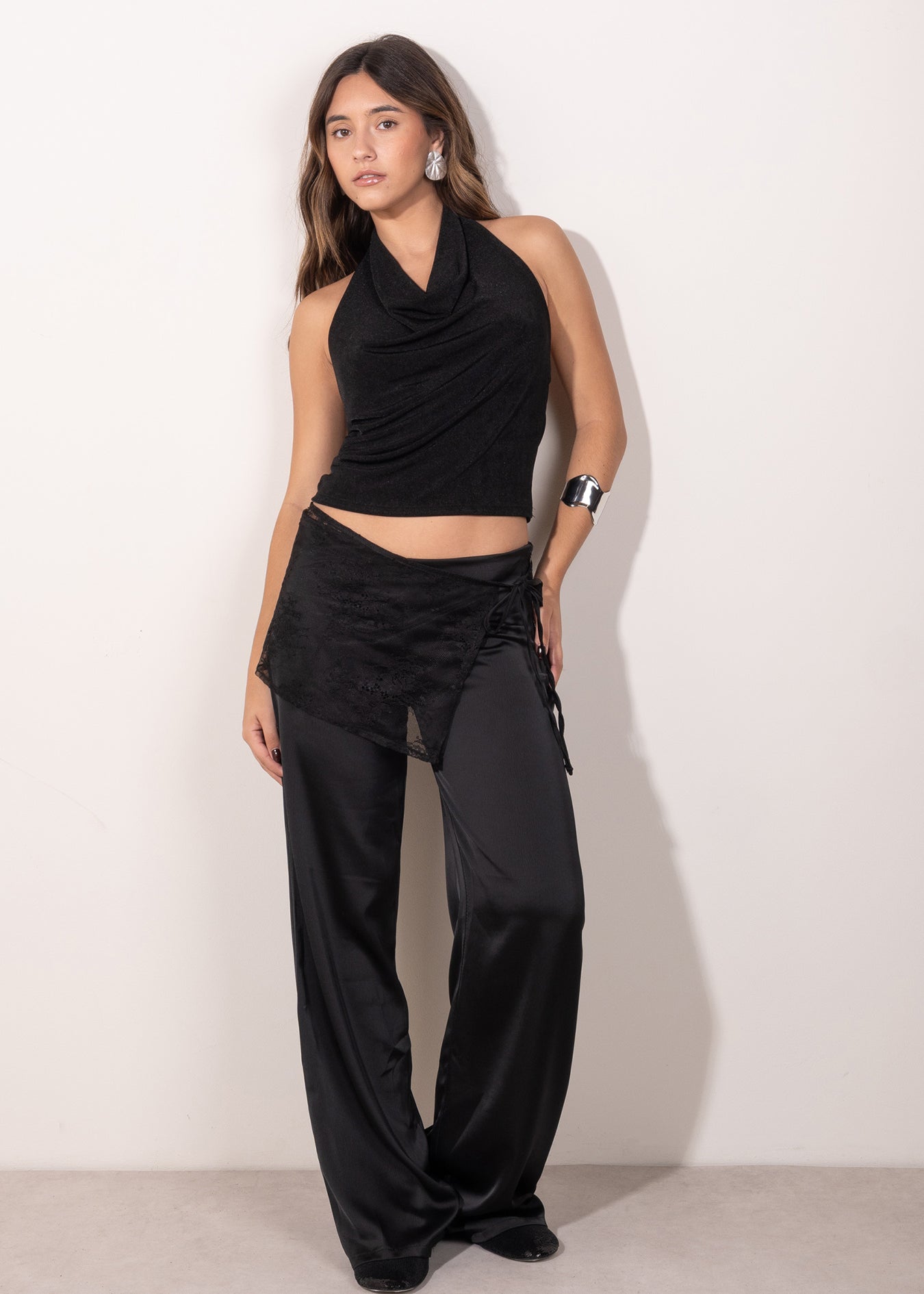 Modelo posando con top negro con escote drapeado tipo halter, estilo elegante y femenino