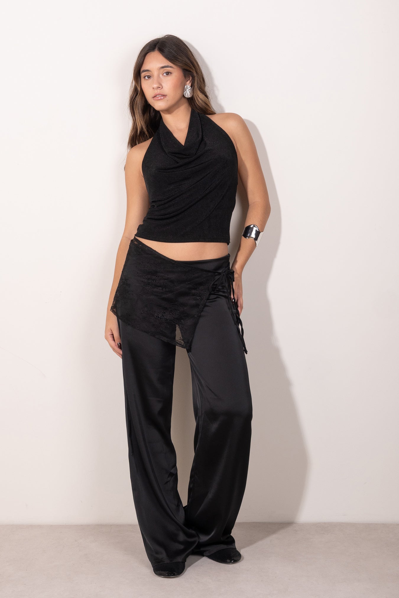 Modelo posando con top negro con escote drapeado tipo halter, estilo elegante y femenino