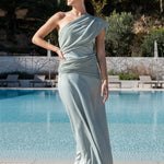 Invitada con vestido largo salvia de caída fluida y un solo hombro, ideal para eventos de noche elegantes.