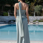 Espalda de vestido de invitada verde salvia con detalle de capa asimétrica que cae desde el hombro.