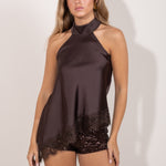 Top marron satinado con cuello halter y detalle de encaje en el bajo, mostrado por una modelo de pie
