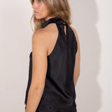 Espalda de  top negro satinado con cuello halter y detalle de encaje en el bajo.
