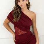modelo con vestido largo granate de fiesta perfecto para eventos especiales, bodas, galas o cenas formales. Diseño asimétrico de un solo hombro. La silueta entallada resalta la figura, mientras que la sutil franja de encaje floral en la cintura añade un toque romántico y sensual, sin perder la clase.
Detalle: Encaje semitransparente en la cintura